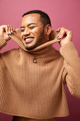 Studio portrait of queer man laughing against purple background
