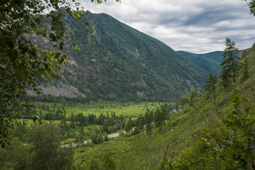 a highway in a valley between mountains covered with forest