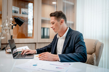 Naklejka premium Businessman looking at a computer monitor during his working day in the office.