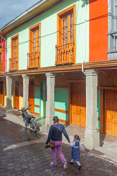 Indigenous Woman With Child Walking To School In Front Of Colonial Style Architecture, Quito, Ecuador.