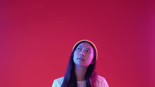 Thinking woman. Decision making. Question choice. Puzzled thoughtful hipster girl offer choosing in colorful neon light on red copy space background.