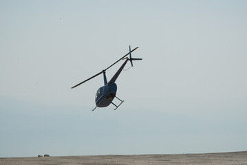 Blue helicopter flying in grey cloudy skies