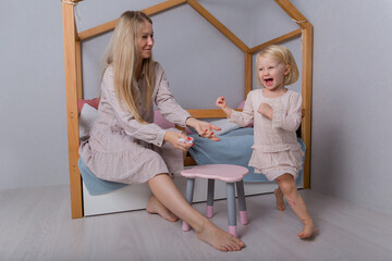 A little blond girl runs away from her mother. Preschool Education.  Mother and daughter playing in...