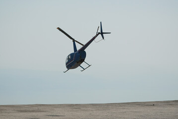 Blue helicopter flying in grey cloudy skies