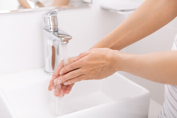 Washing hands under the flowing water tap. Hygiene concept hand detail. Washing hands rubbing with soap for corona virus prevention, hygiene to stop spreading corona virus in or public wash room.