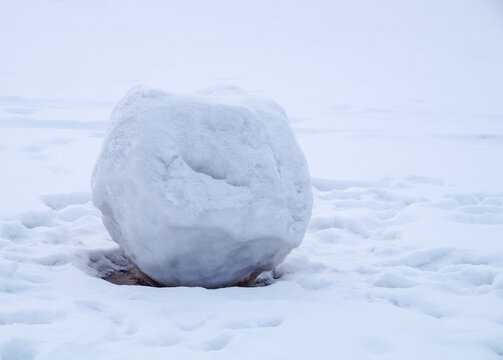 A big snowball of sleet.Melting snow and the ground is visible.Thaw, the approach of spring.