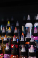Bottles of multicoloured tattoo inks. Tattoo salon. Selective focus, blurred.