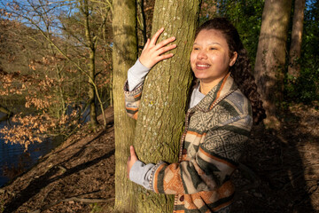 Smiling young woman hugging tree