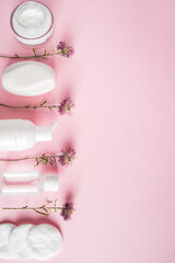 Cosmetic products on pink background. White bottles of cream and lotion. Spa accessories, body care. Wellness concept.