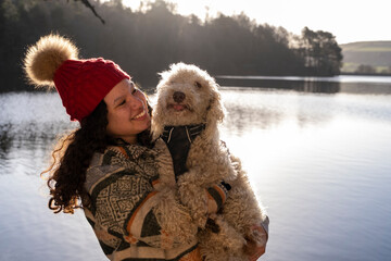 Young woman holding dog at lake