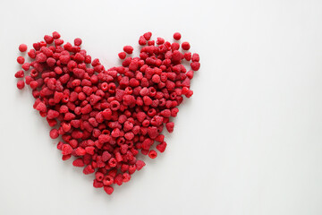 Fototapeta na wymiar Fresh raspberries in the shape of a heart on a white background