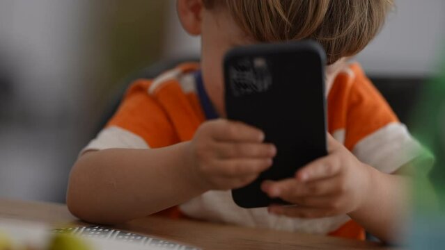 Annoyed little boy using phone upset child holding cellphone