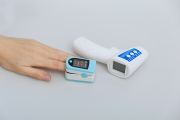 Pulse oximeter and thermometer gun on white background. Infrared isometric thermometer gun to check...