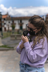 Girl with face mask hugging a street puppy in the street