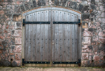 An old castle door set into a castle wall. Large black hinges support the wooden door. 