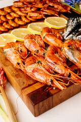 Fried langoustines and fried mussels with sauce and fried shrimps and sliced lemon on wooden cutting board and jacinths
