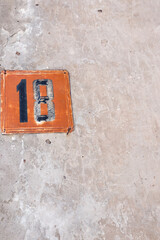 rusty house number eighteen on a concrete wall