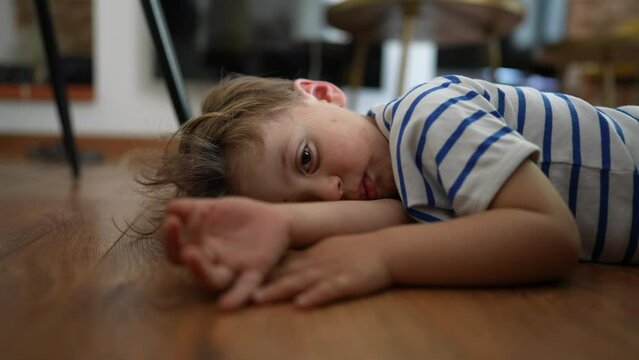 Bored kid Child feeling boredom lying on floor at home with nothing to do