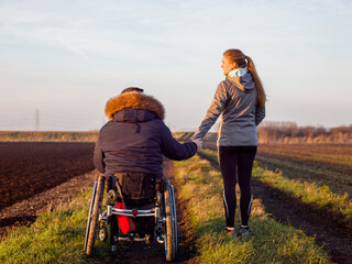 Rear view of woman and man on wheelchair in field