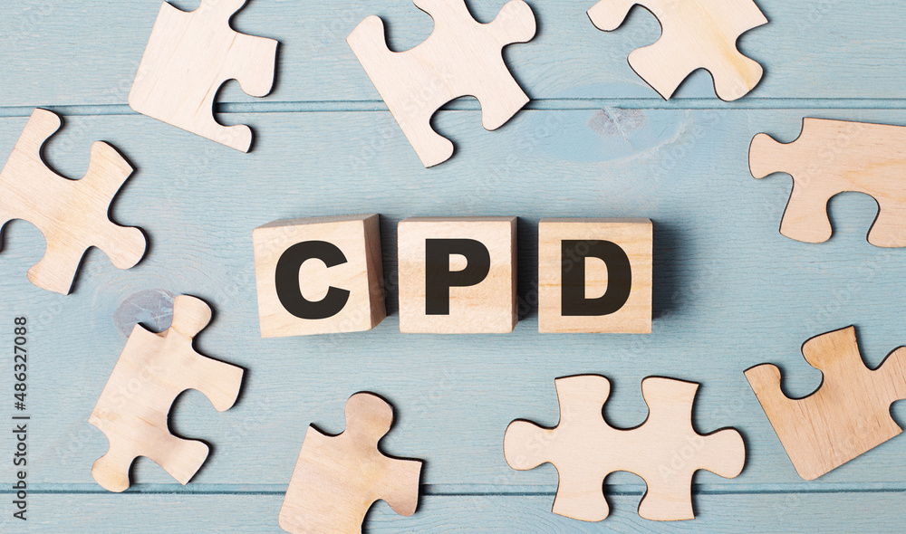 Poster blank puzzles and wooden cubes with the text cpd continuing professional development lie on a light 