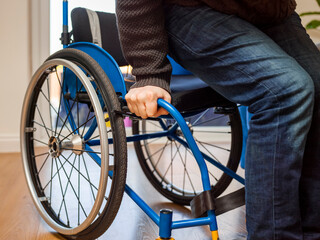 Obraz premium Mid section of disabled man sitting on wheelchair at home