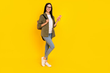 Fototapeta na wymiar Full size photo of nice young lady hold telephone wear bag spectacles shirt jeans shoes isolated on yellow background