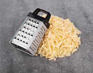 A mound of grated parmesan with a small grater