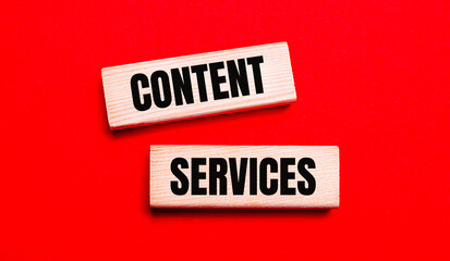 On a bright red background, there are two light wooden blocks with the text CONTENT SERVICES