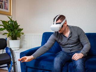 Man with VR goggles sitting on sofa next to wheelchair