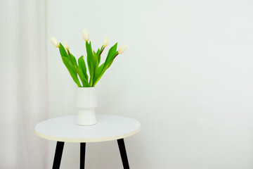 White tulips in a white vase on the table