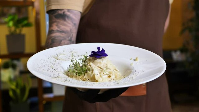 Pasta with cream and parmesan, decorated with edible flowers and microgreen close-up