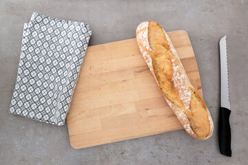 French baguette bread on a wooden cutting board with knife and towel