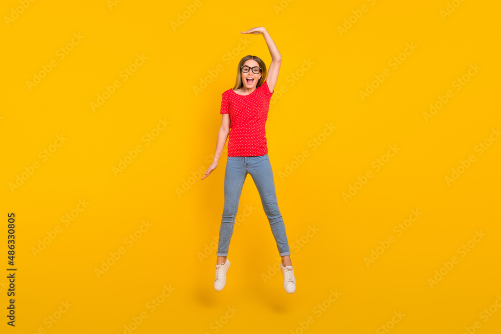 Wall mural Full body photo of young cheerful girl jump show hand big high measure isolated over yellow color background