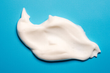 Soft white foam, soft soap foam texture or shaving cream on blue background copy space.
