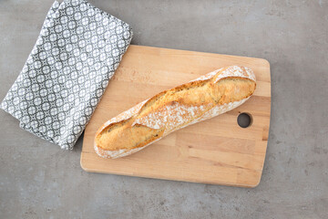 French baguette bread on a wooden cutting board with towel