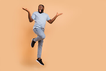 Fototapeta na wymiar Full length body size view of attractive cheerful lucky guy jumping rejoicing copy space isolated over beige pastel color background