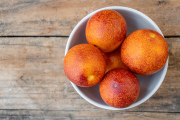 Sanguinelli class oranges, grouped in a white bowl, on wooden background.