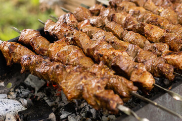delicious bbq kebab grilling on open grill, outdoor kitchen. food festival in city. tasty food roasting on skewers, food-court. summer picnic