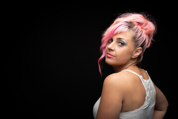 Caucasian blonde woman with pink hair and green eyes smiling at camera looking sideways.