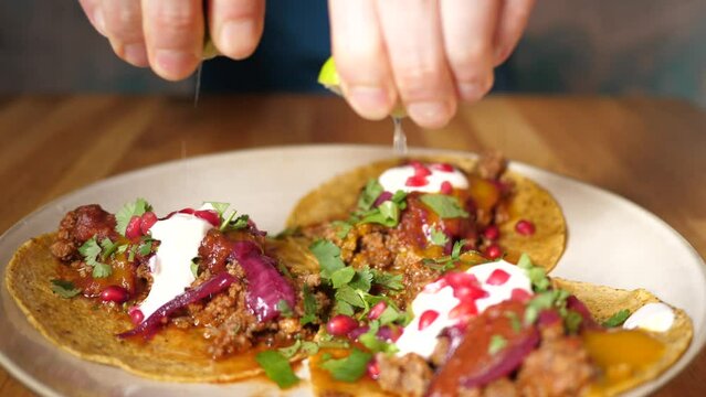 Man squeeze lime juice drops pouring tacos meal in Mexican cuisine restaurant