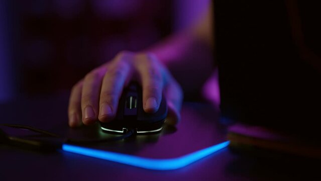 Close-up hands of gamer playing video game using illuminated mouse.Male hand using mouse. Background with neon lights.