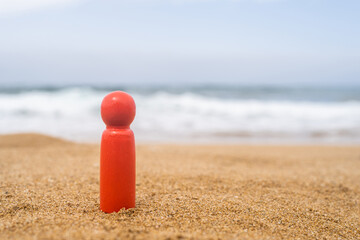 Wooden one, alone figure of red, dark color of man on the sand of beach with sea view. Concept of vacation. individual traveller