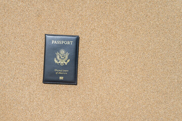 American passport in a cover lying on the sand of the beach. Concept of summer travel, tourism, holiday, vacation.