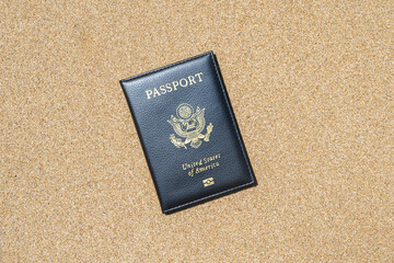 American passport in a cover lying on the sand of the beach. Concept of summer travel, tourism, holiday, vacation.