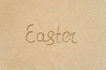Drawing easter word on the sand on the beach.