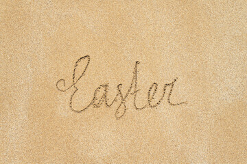 Drawing easter word on the sand on the beach.