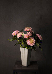 Fototapeta na wymiar Spring background. Dahlias in pink in a glass vase on a gray background.