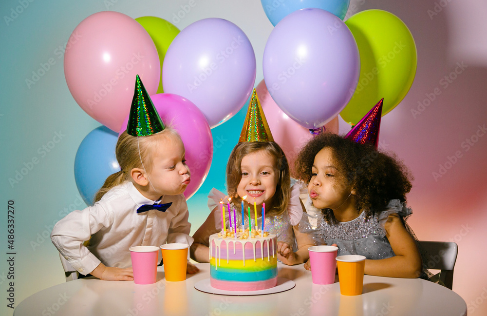 Wall mural kids birthday party. children blowing candles on cake together