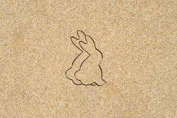Drawing creative two easter bunny on the sand on the beach.