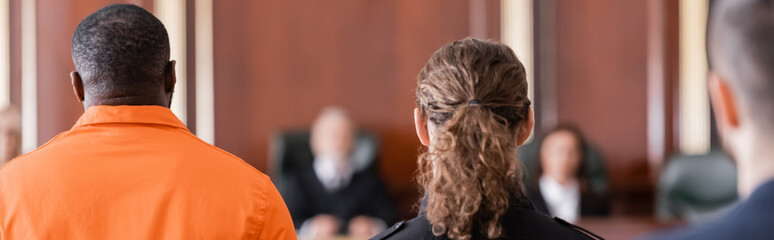 back view of accused african american man, bailiff and juryman in courtroom, banner